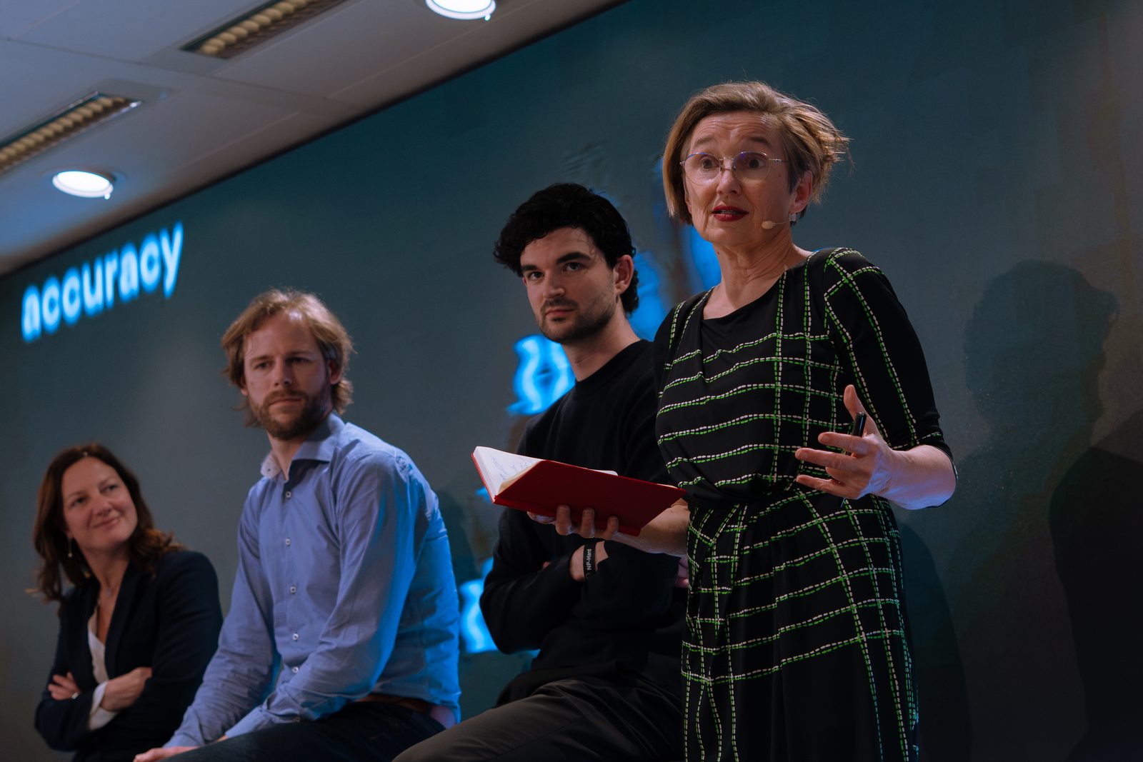 Monique van Dusseldorp moderating a panel, standing with notebook in hand